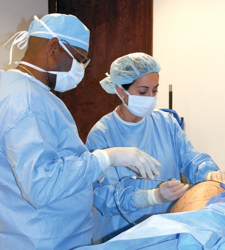 Dr. Reynolds observes as trainee learns proper liposuction technique.