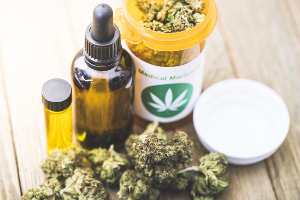 Medical marijuana plants appear with a pill bottle and medicine droper on a wood table.